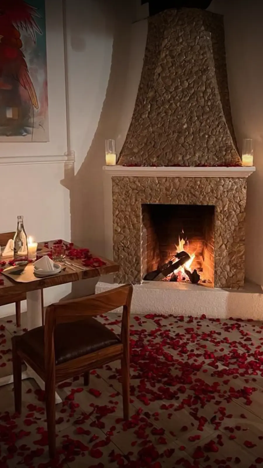Table for two by the stone fireplace at Rosanta, with candles and rose petals on the floor