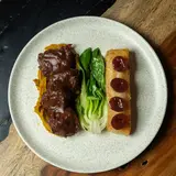 Brisket in Bordelaise sauce with plantain purée, bok choy and a yuca bar topped with grapes