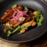 Pork ribs with red onion and purée, next to a cocktail