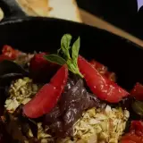 Baked cheese with a pepitoria crust and macerated strawberries in a cast-iron skillet