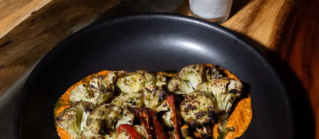 Grilled cauliflower served on a wooden table by candlelight