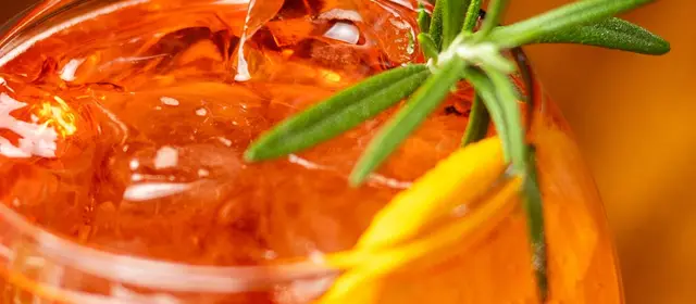 Cocktail with ice, orange and rosemary on the bar