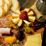 Board of cheeses and cured hams with bread, pickles and fruit